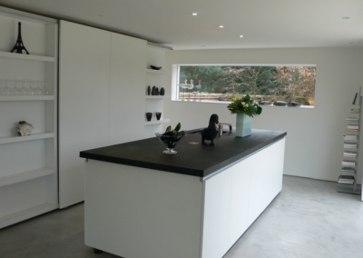 The black granite worktop and white walls blend with the floor